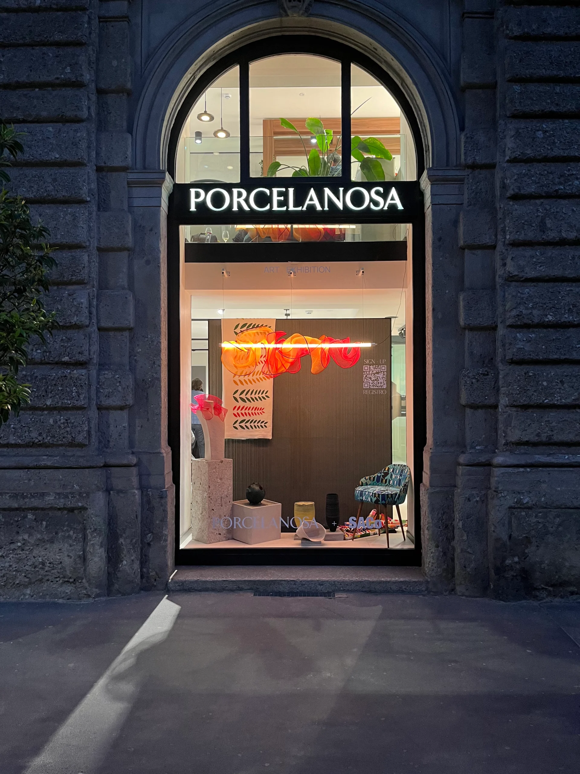 The photo frames a display case in the Porcelanosa shop where the "Cloud" lamp by LZF Lamps can be seen together with other designs by collaborators of the exhibition. 